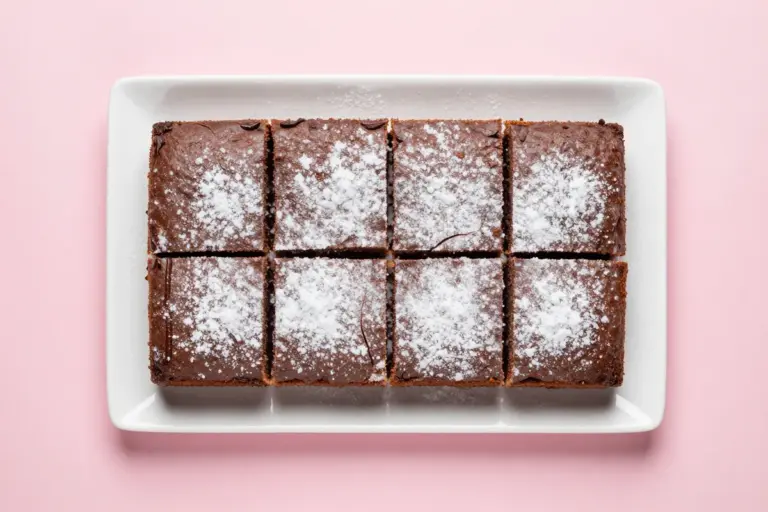 Whole chocolate applesauce cake cut into squares on a white rectangular platter.