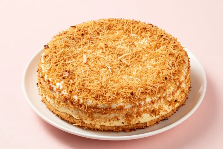 Whole coconut macaroon cake with toasted shredded coconut on a white plate
